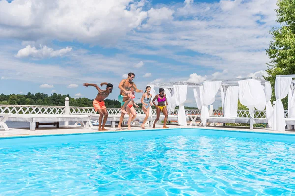Gente multiétnica saltando a la piscina - foto de stock