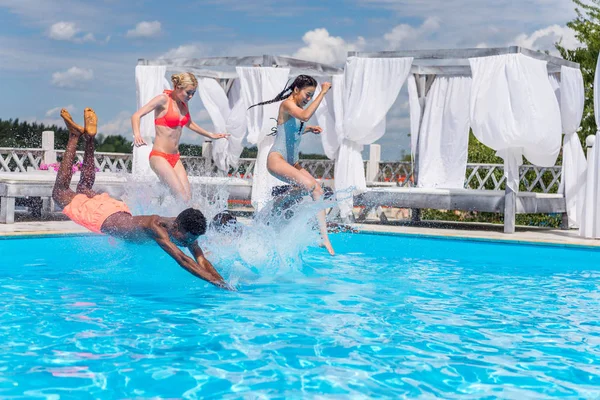 Pessoas multiétnicas pulando na piscina — Fotografia de Stock