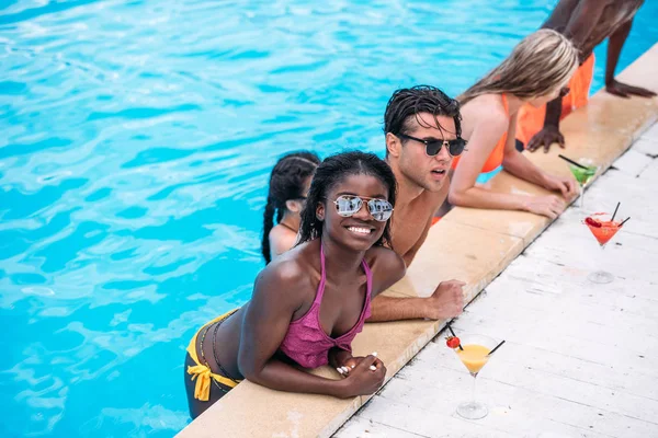 Personnes multiethniques avec cocktails dans la piscine — Photo de stock