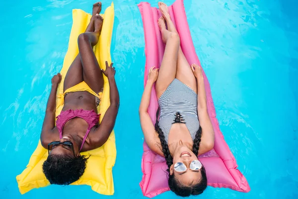 Multiethnic women on inflatable mattresses in pool — Stock Photo