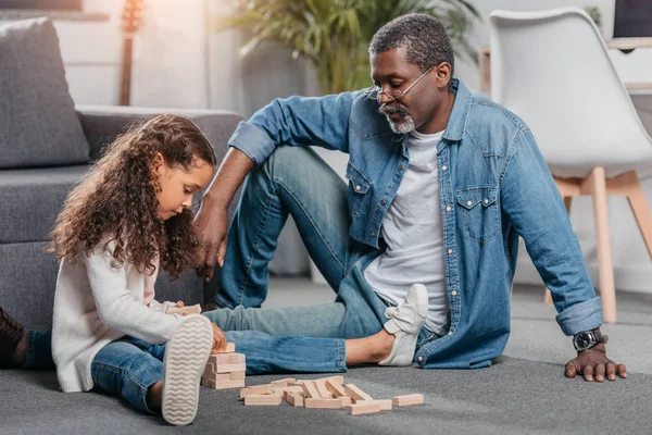 Chica jugando bloques juego con padre - foto de stock