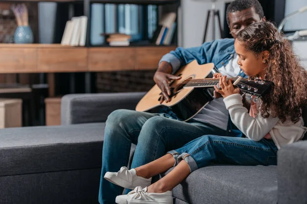 Uomo che suona la chitarra con la figlia a casa — Foto stock