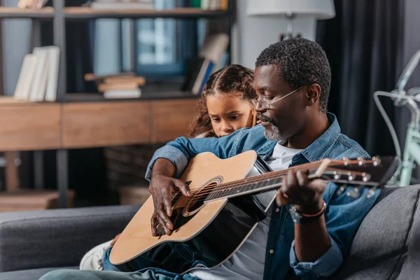 Uomo che suona la chitarra con la figlia a casa — Foto stock