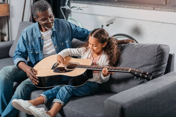 Hombre enseñando hija a tocar la guitarra - foto de stock