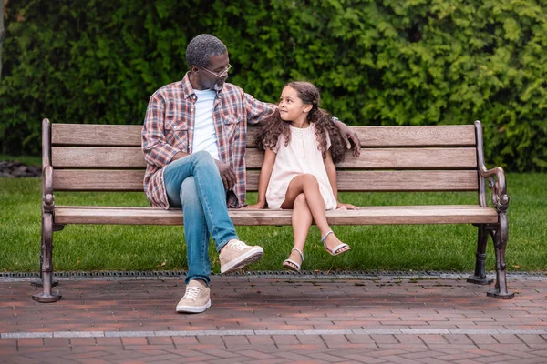 Girl and grandfather sitting on bench — Stock Photo