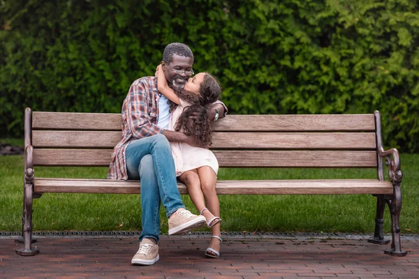 Chica abrazando y besando a su abuelo - foto de stock