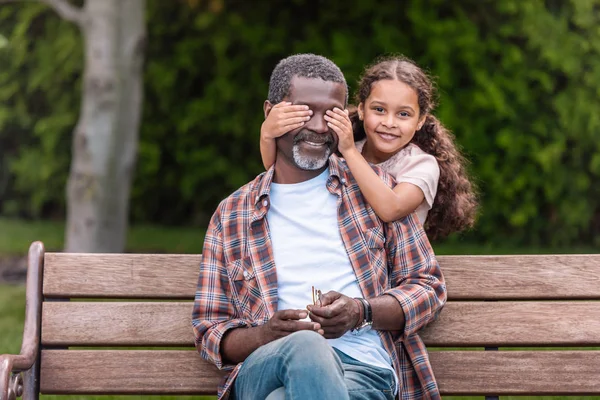 Chica cerrando los ojos de su abuelo — Stock Photo