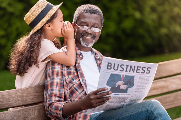 Kleines Mädchen flüstert ihrem Großvater zu — Stockfoto