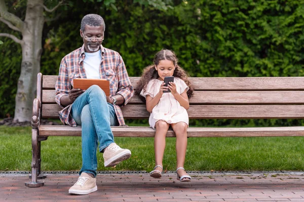 Girl and grandfather using digital devices — Stock Photo