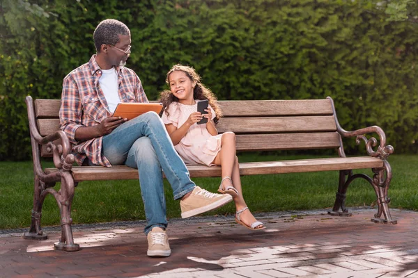 Girl and grandfather using digital devices — Stock Photo