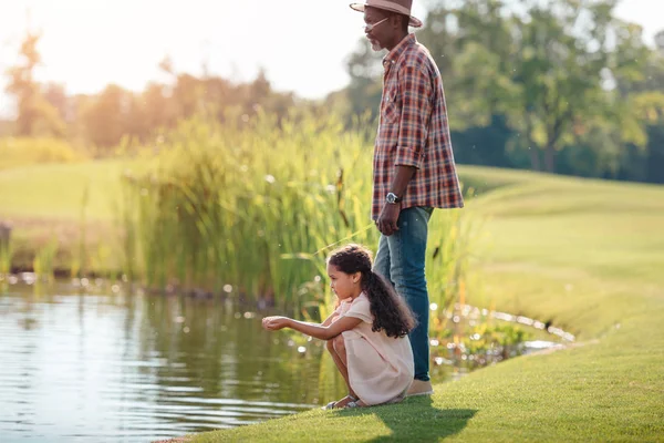 Granddaughter and grandfather standing at lake — Stock Photo