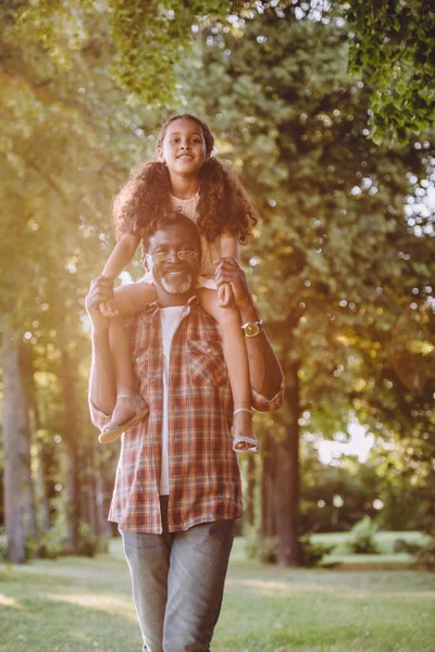 Petite-fille assise sur les épaules du grand-père — Photo de stock