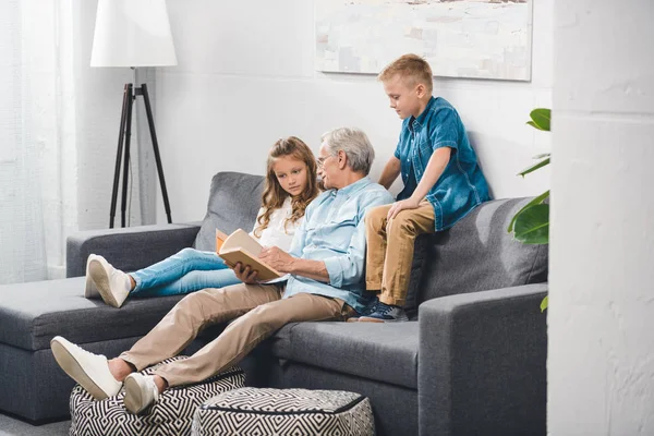 Grandfather and grandchildren reading book — Stock Photo