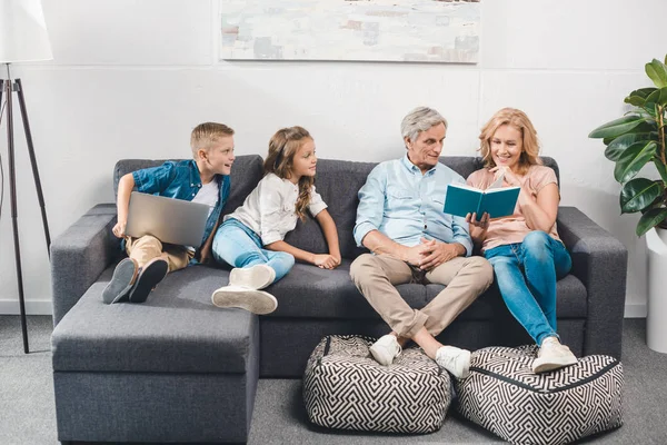 Family with book and laptop — Stock Photo