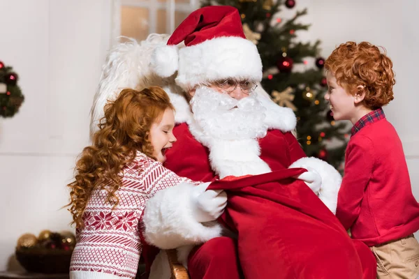 Enfants à la recherche de cadeaux dans le sac santas — Photo de stock