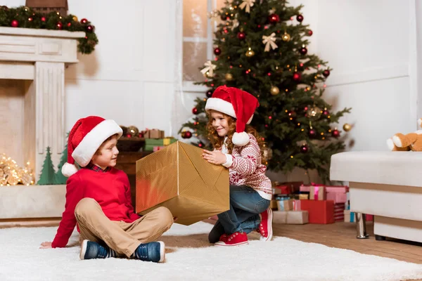 Kids in santa claus hats with gift — Stock Photo