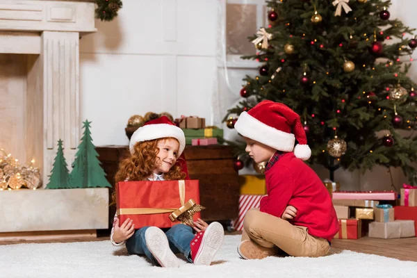 Kids in santa claus hats with gift — Stock Photo