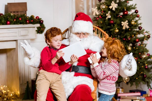 Papai Noel e crianças com dispositivos digitais — Fotografia de Stock