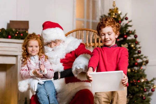 Santa Claus y niños con dispositivos digitales - foto de stock