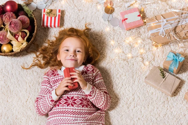 Niño acostado en el suelo con regalos - foto de stock