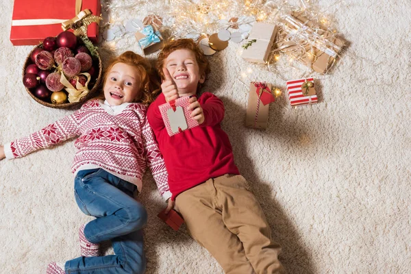 Niños acostados en el suelo con regalos - foto de stock