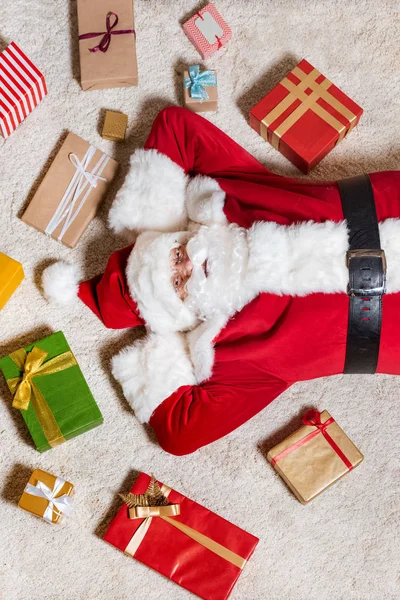 Papai Noel deitado no chão com presentes — Fotografia de Stock