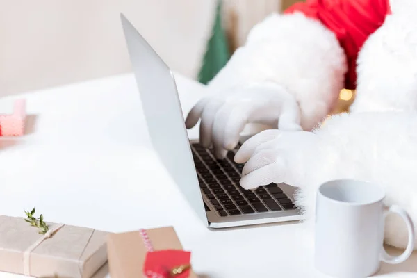 Санта-Клаус печатает на ноутбуке — стоковое фото