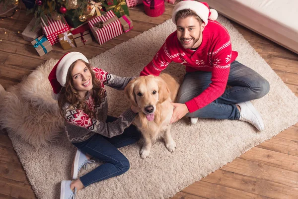 Paar in Weihnachtsmützen mit Hund — Stockfoto