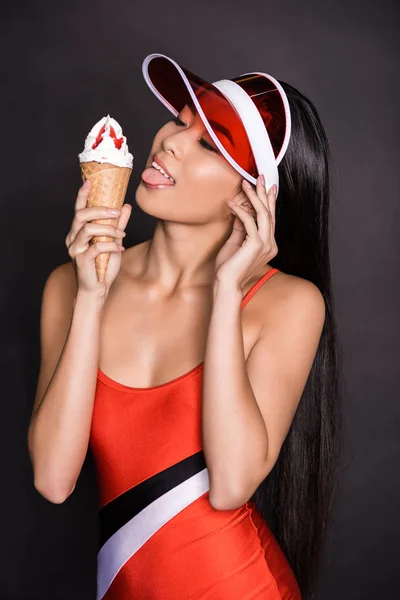 Femme en maillot de bain et visière léchant glace — Photo de stock