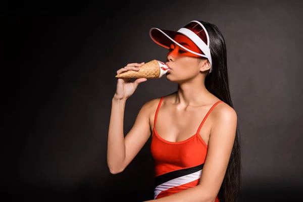 Mujer en traje de baño y visera comiendo helado - foto de stock