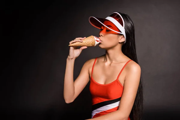 Mujer en traje de baño y visera comiendo helado — Stock Photo