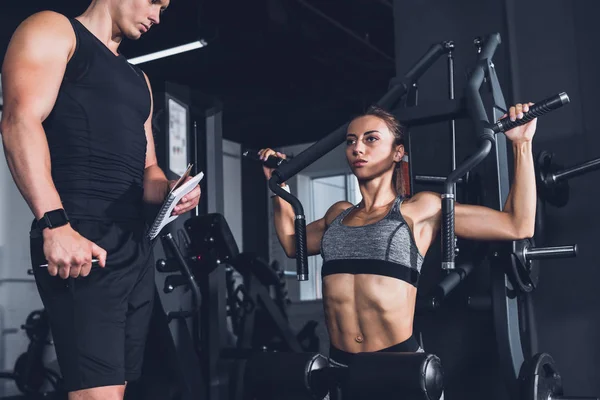 Entrenador y mujer deportiva en el gimnasio - foto de stock