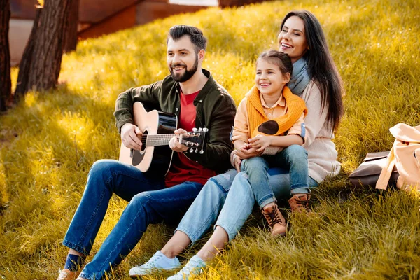 Família sentada em uma colina gramada — Fotografia de Stock