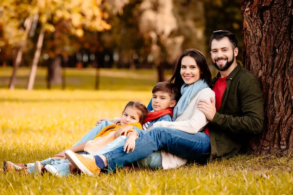 Familia feliz apoyada en el árbol - foto de stock