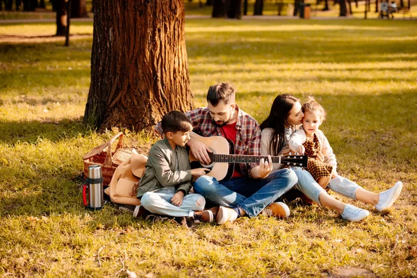 Familia en picnic tocando la guitarra - foto de stock