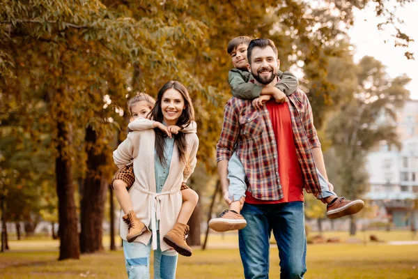 Pais dando às crianças passeio de piggyback — Fotografia de Stock