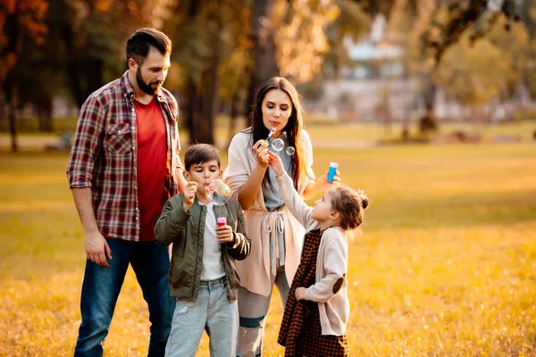 Family with children blowing bubbles — Stock Photo