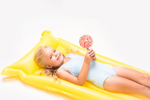 Niño con piruleta en colchón de natación - foto de stock