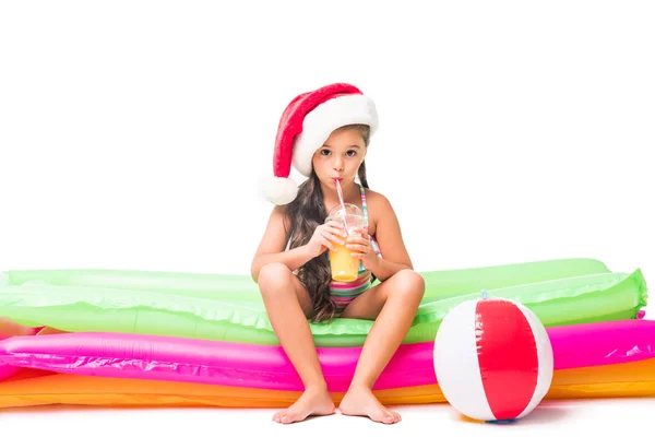 Niño en traje de baño y sombrero de santa con jugo - foto de stock