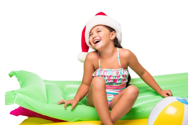 Child in santa hat on swimming mattresses — Stock Photo