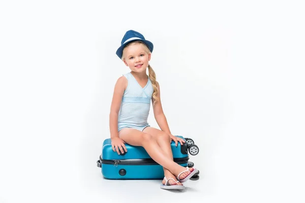 Ребенок в купальнике сидит на чемодане — стоковое фото