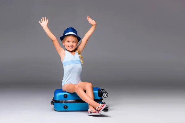 Ребенок в купальнике сидит на чемодане — стоковое фото