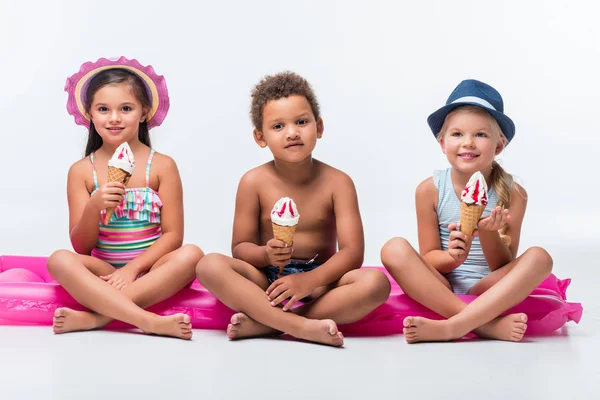 Niños multiétnicos comiendo helado - foto de stock