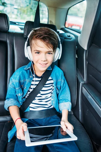 Хлопчик з планшетом слухає музику в машині — стокове фото