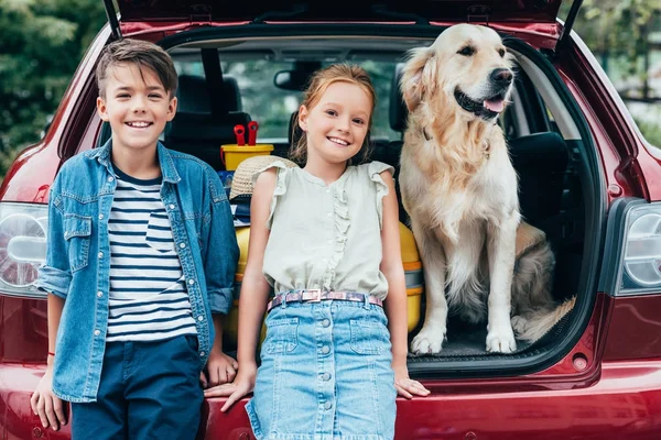Enfants avec chien dans le coffre de la voiture — Photo de stock
