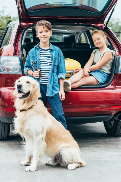 Enfants avec chien dans le coffre de la voiture — Photo de stock