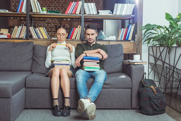 Coppia con libri in biblioteca — Foto stock