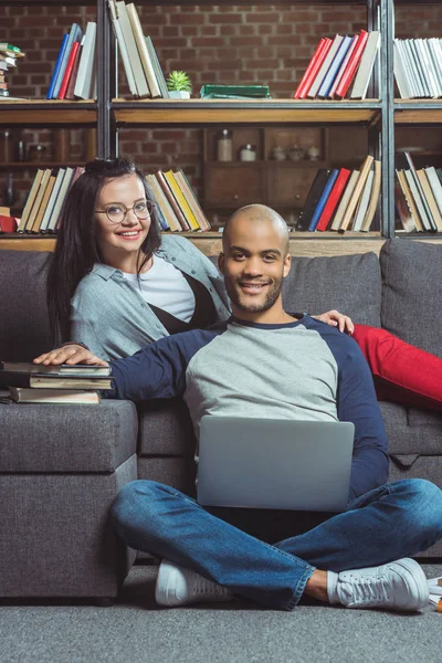 Estudiantes multiétnicos con ordenador portátil y libros - foto de stock