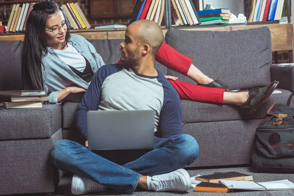 Étudiants multiethniques avec ordinateur portable et livres — Photo de stock