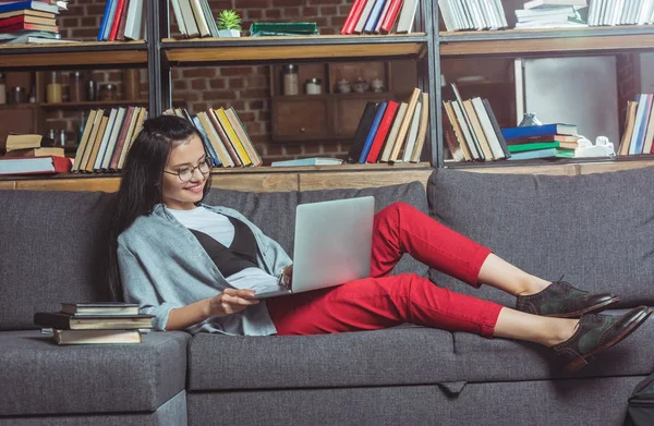 Chica usando el portátil en la biblioteca - foto de stock